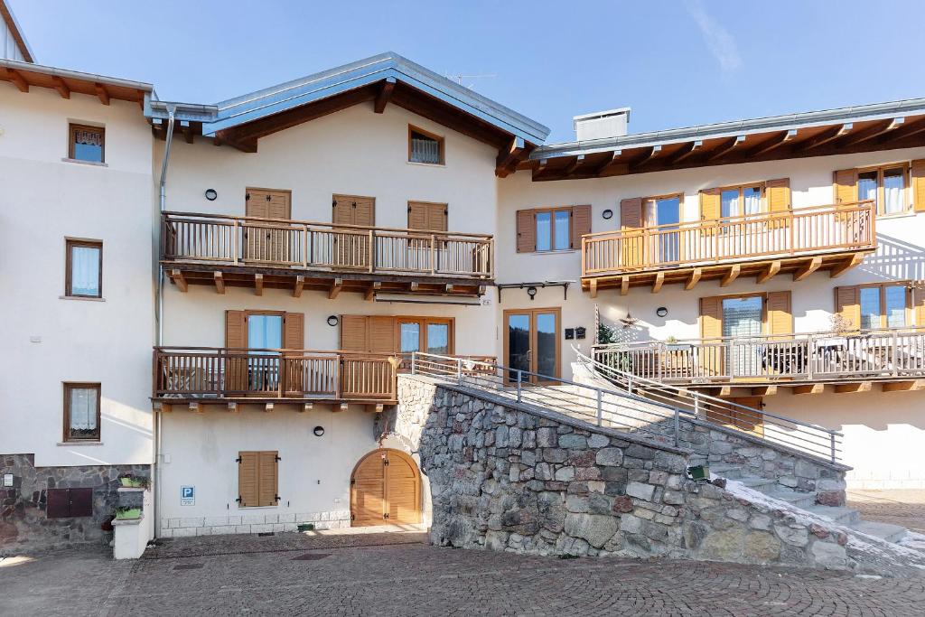 a large building with balconies and a stone wall at Appartamento Lory in Cavedago