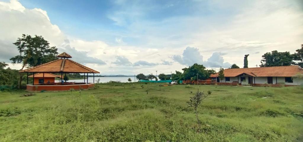 a gazebo in a field next to a house at Trogon resort in Kabini River