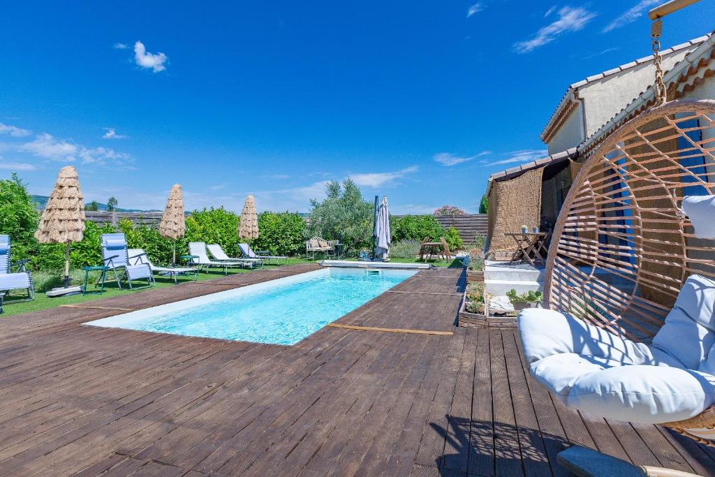 a swimming pool on a wooden deck with chairs around it at Maison dans la Drôme Piscine privée in Montélimar