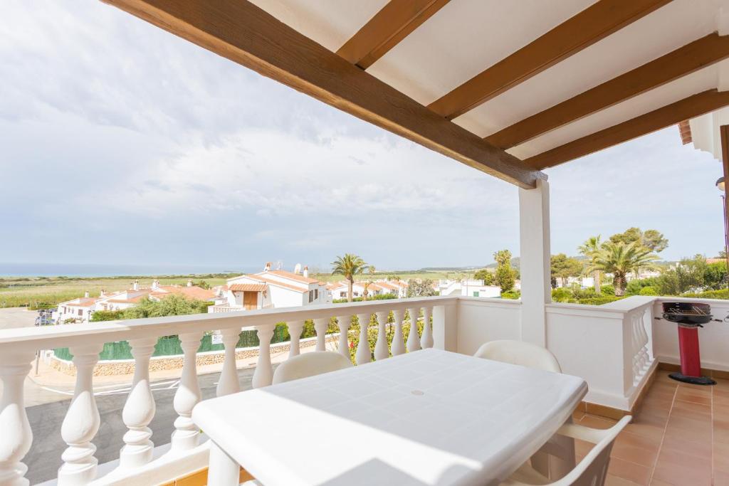 a white table on a balcony with a view of the ocean at Villa Loes in Menorca