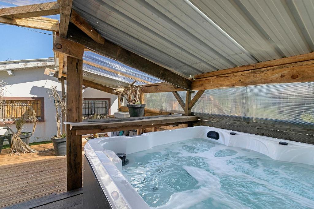 a hot tub on a deck with a roof at Chalet de Ferme - Spa - Gironde in Les Églisottes-et-Chalaures