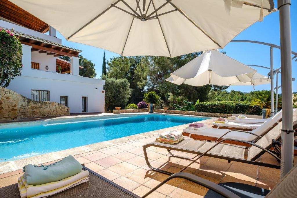 a swimming pool with two chairs and an umbrella at Can Bernat in Can Furnet