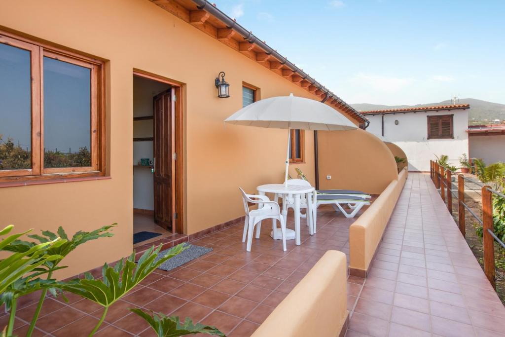 a patio with a table and chairs and an umbrella at Casa Quemahierro 2 in Icod de los Vinos