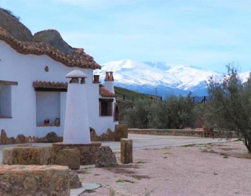 a white building with a mountain in the background at Los Cerezos in Benalúa de Guadix