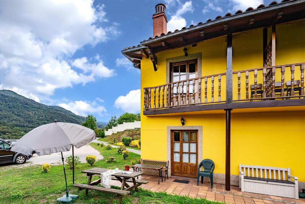 ein gelbes Haus mit einem Picknicktisch und einem Sonnenschirm in der Unterkunft Socastillo A in Fresnedo