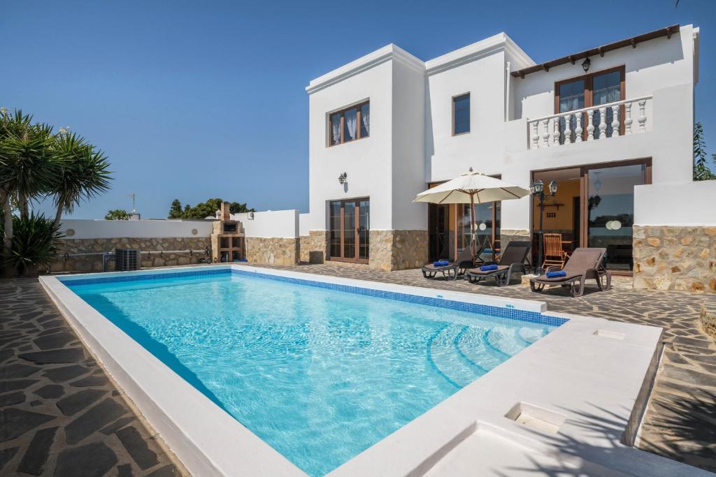 a villa with a swimming pool in front of a house at Villa María in Tinajo