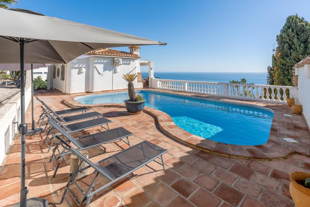 a swimming pool with chairs and an umbrella at Casa Romantica in Salobreña
