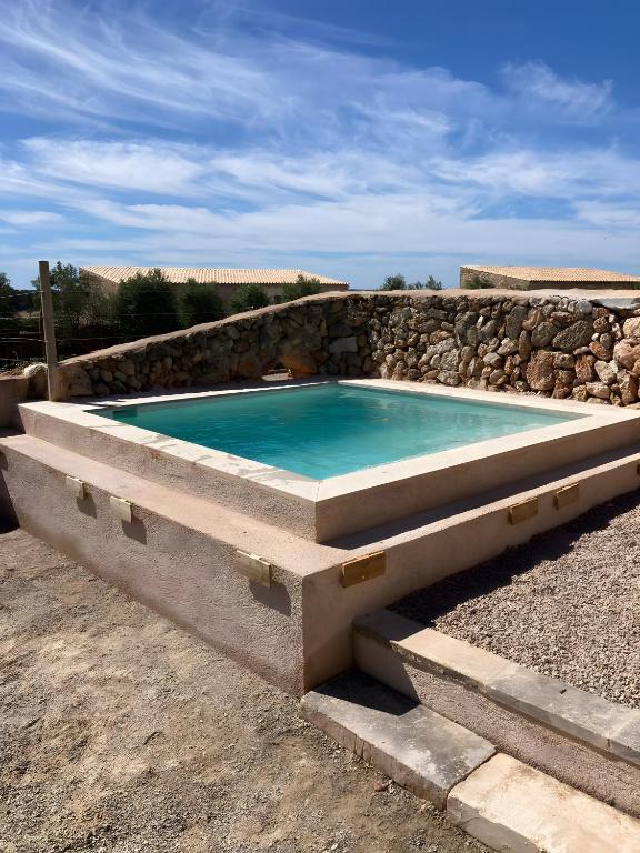 a swimming pool with a stone retaining wall and a stone at Son Rossinyol Nou - Sa Bovera in Islas Baleares
