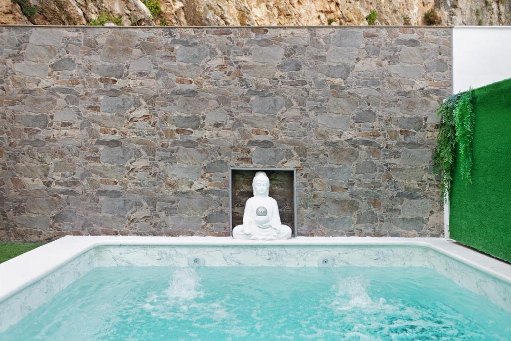 a buddha statue sitting next to a swimming pool at Villa Españolillas in Olvera
