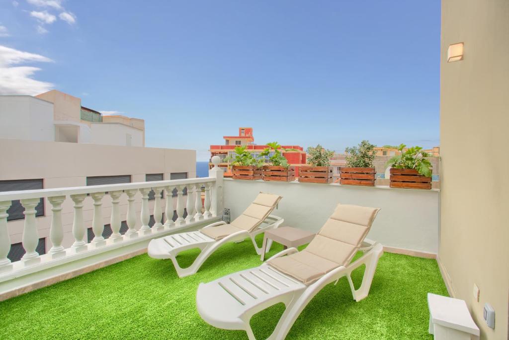a balcony with two chairs and green grass at Luxury Ático Plaza in Playa de San Juan