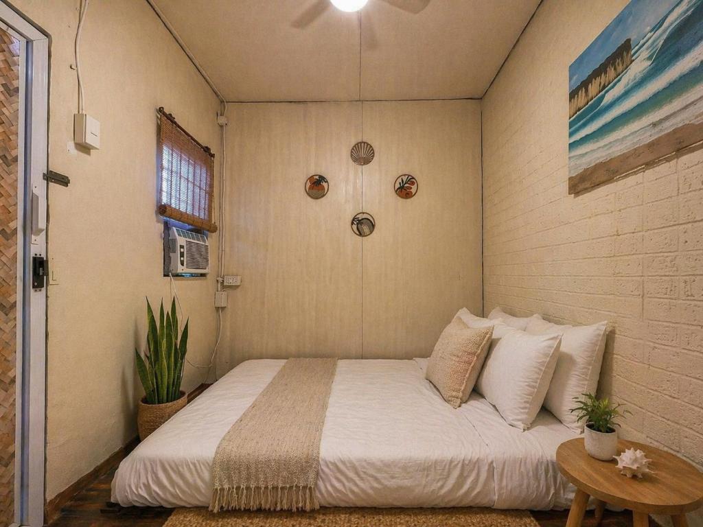 a bedroom with a bed with white sheets and pillows at The Stoked Hideout - Bagasbas Beach in Daet