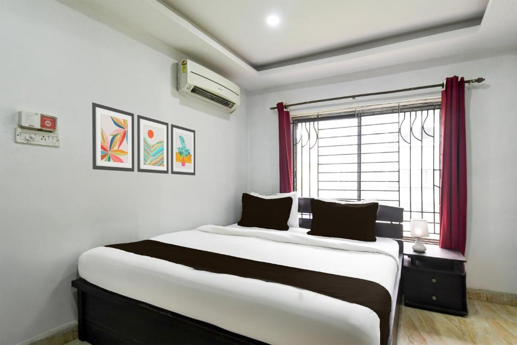 a bedroom with a large bed with a window at Hotel O New Alipore in Kolkata
