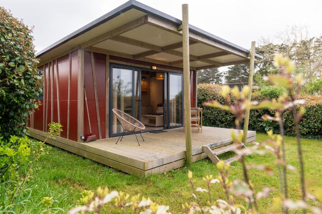 a small red cottage with a wooden deck at Chalet 20m2 - Ile Vierge in Plouhinec