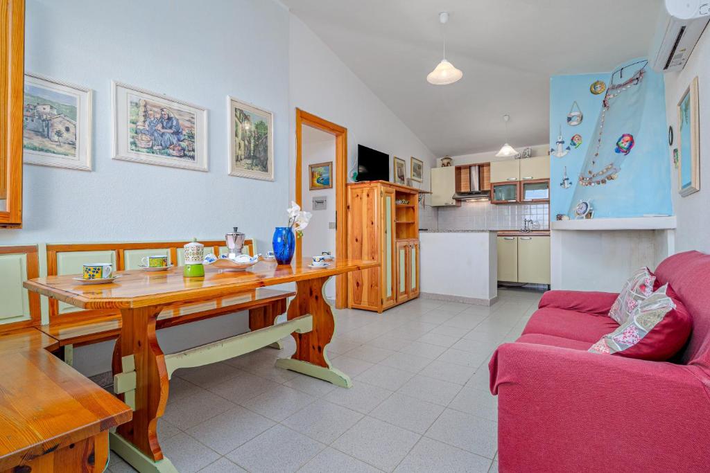 a living room with a wooden table and a red couch at Quadrilocale Le Colonne in Lu Lioni