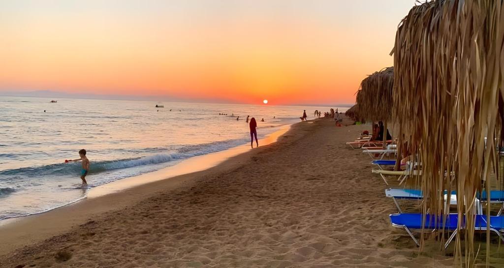 a sunset on the beach with people in the water at Santorini Studios Pleasure in Perissa
