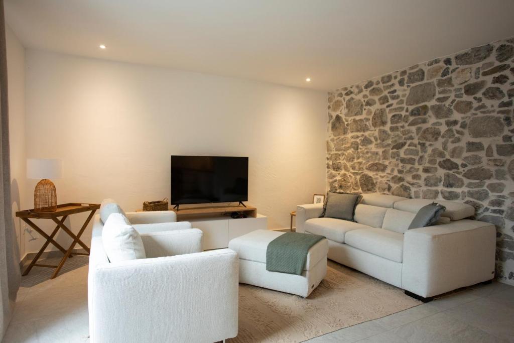 a living room with white furniture and a stone wall at Appartement de charme - La Tour in La Tour