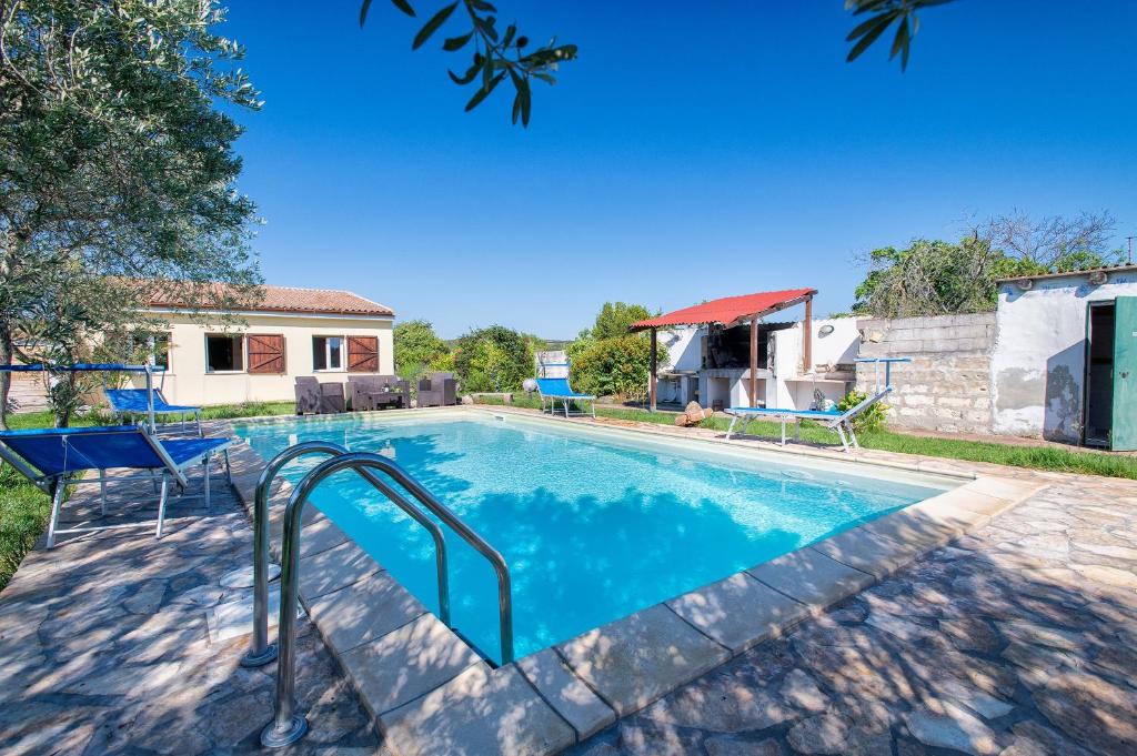 a swimming pool in a yard with a house at Gadem House in Alghero