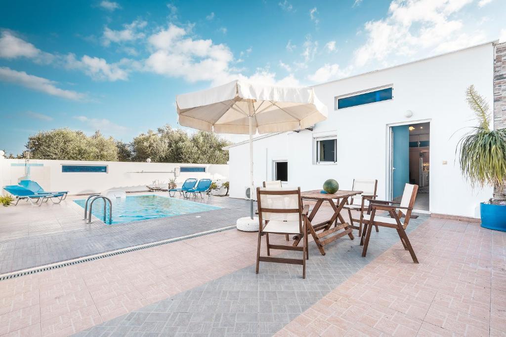 a patio with a table and chairs and a pool at Beach Pearl in Lachania