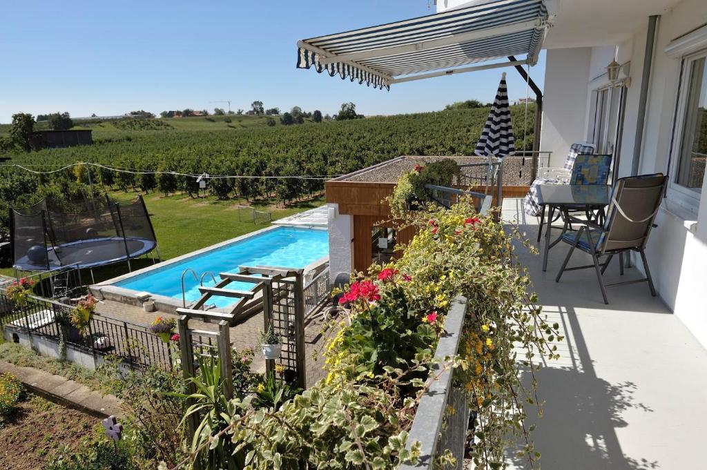 a patio with a swimming pool and some flowers at Obst- und Ferienhof Schäfler in Hattnau