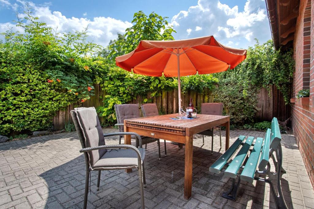 a wooden table with an umbrella and two benches at Ferienhaus Dorfidyll in Bugewitz