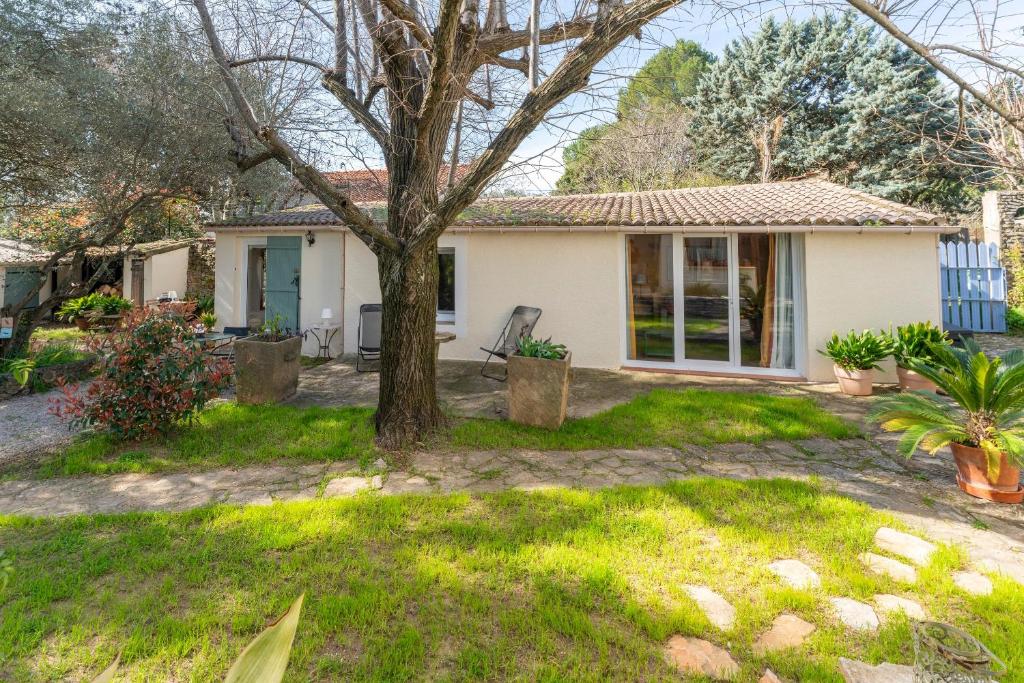 a white house with a tree in the yard at Mazet à Nimes in Nîmes