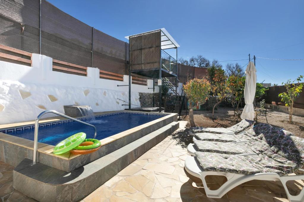 a swimming pool with two lounge chairs and an umbrella at Finca Keyfer in Vilaflor