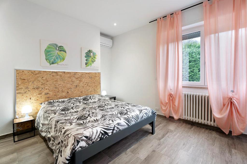 a bedroom with a bed and a window with pink curtains at Sweet Home Apartments Peperoncino in Arona