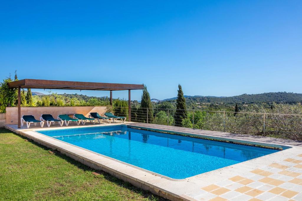 a swimming pool with chairs and a gazebo at Finca Bionic in Artá
