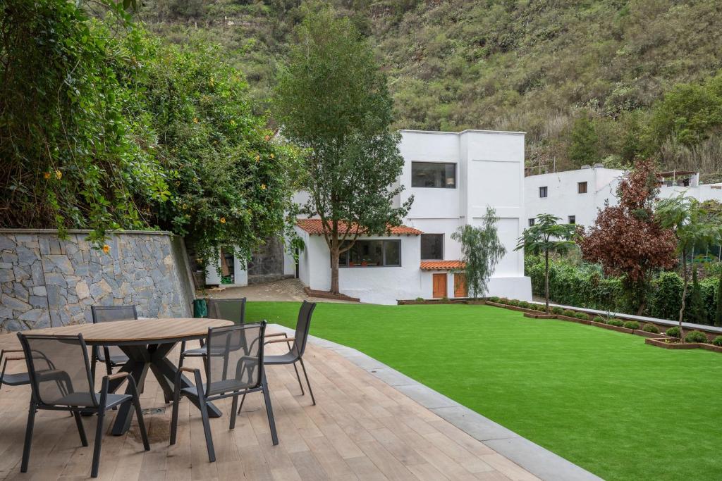 a patio with a table and chairs and a lawn at Finca Los Tilos Moya in Moya