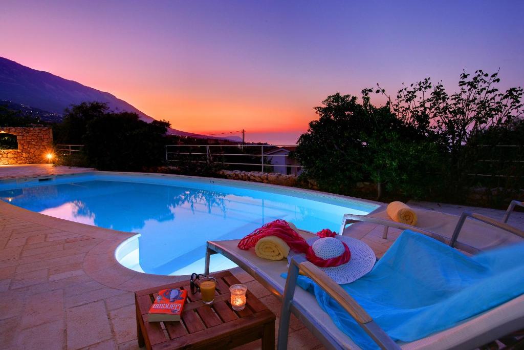 a large swimming pool with a bench and a sunset at Villa Petalida Ideales Resort in Kefallonia
