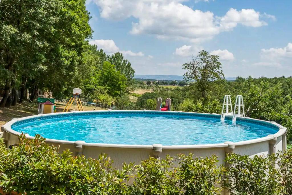 a large swimming pool in a yard with trees at Faetino - Pavone in Colle di Val d'Elsa