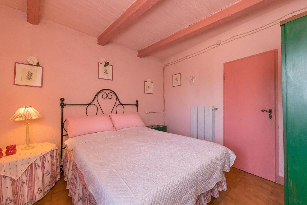a pink bedroom with a bed and a lamp at Casina nel Borgo Antico in Bibbona