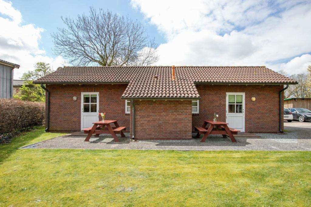 a brick house with two picnic tables in front of it at Apartment Eulenhof 2 in Bordelum