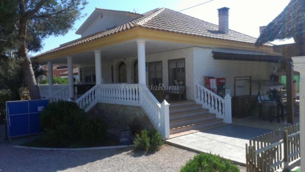 a small white house with a porch and stairs at Chalet Del Sol in Puerto Lumbreras