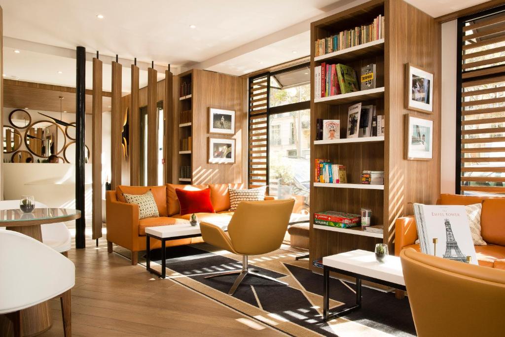a library with orange chairs and bookshelves at Hôtel Eiffel Turenne in Paris