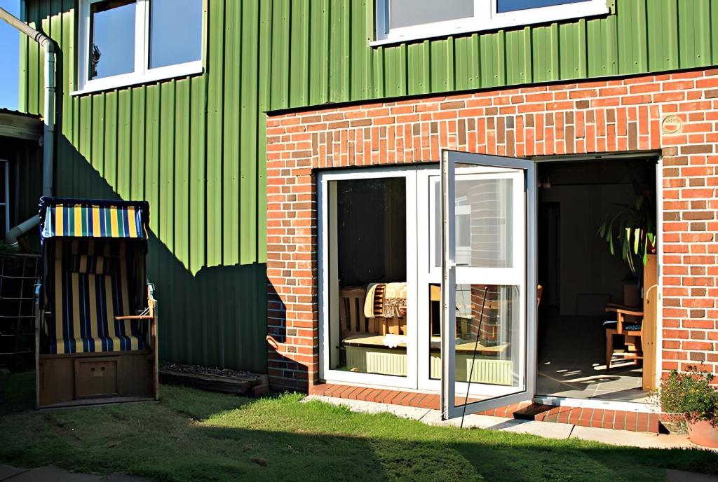 a green building with a sliding glass door on it at Hof Islandpferde von der Holstenau in Eggstedt