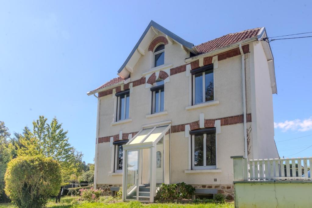 a large white house with a porch at Charmant Cottage - Saint-Junien in Saint-Junien