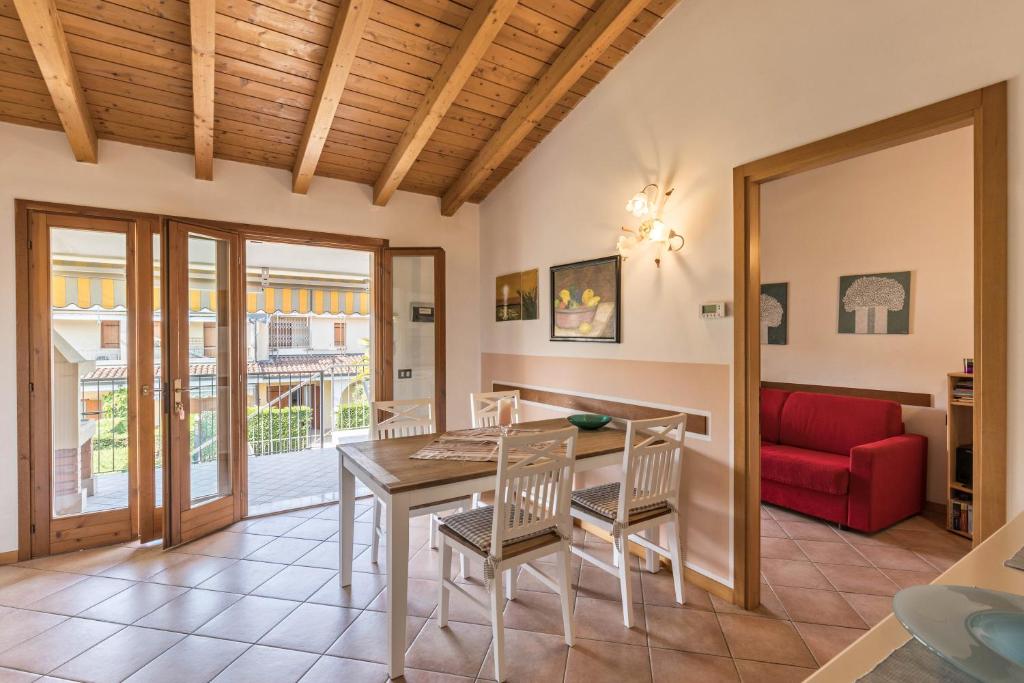 a dining room with a table and chairs and a red couch at Apt Gardasee Lazise Colá in Colà di Lazise