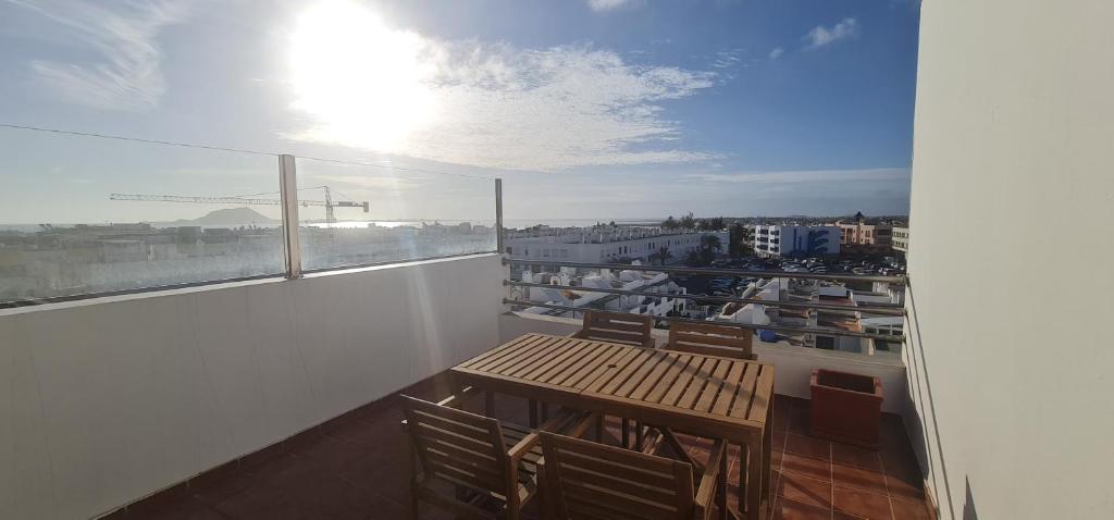 a balcony with a wooden table and a view of a city at Apartamento La Palma Corralejo in Corralejo