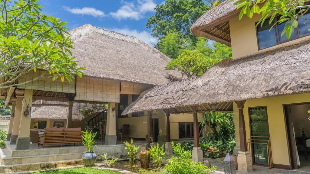 an exterior view of a house with a straw roof at Villa Layangan - Two Bedrooms with Pool Access in Sanur