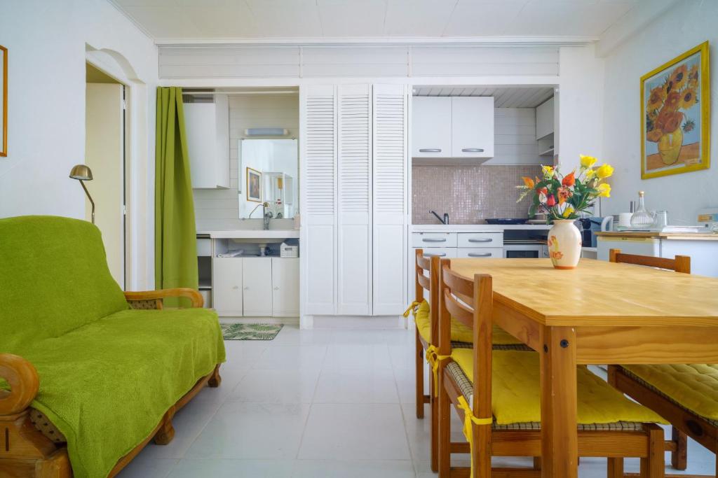 a kitchen and dining room with a table and a green couch at Logis Helena in Elne