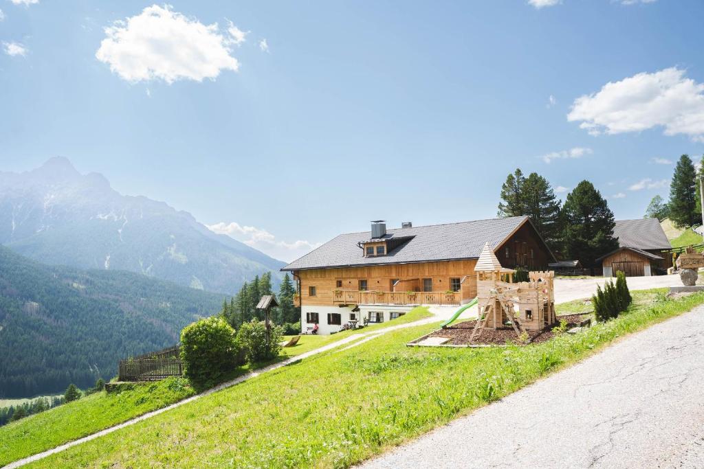 a house on a hill next to a road at Egorta - Egarterhof Sexten in Sesto