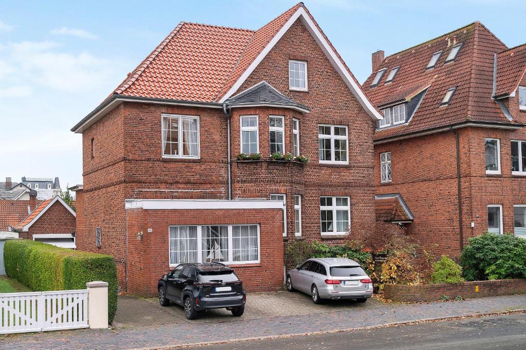 two cars parked in front of a brick house at Haus Margarete Christel Winkelmann in Cuxhaven