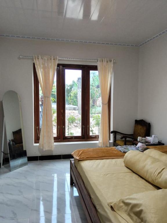 a bedroom with two beds and a large window at Sekar Homestay in Bantul