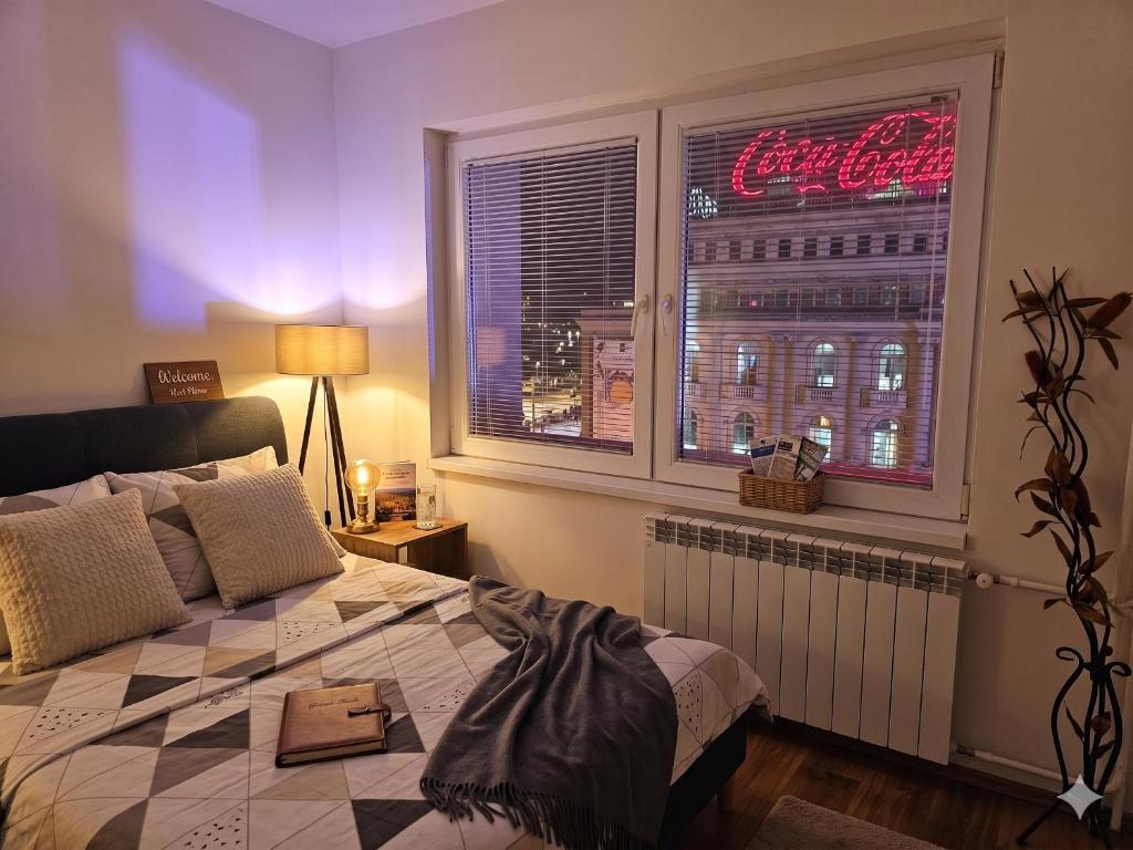 a bedroom with a bed and a window with a neon sign at Exclusive Apartment Main Square FREE PARKING in Skopje