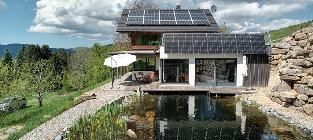 a house with solar panels on top of a pond at Haus am Teich mit privater Sauna in Sankt Leonhard bei Freistadt