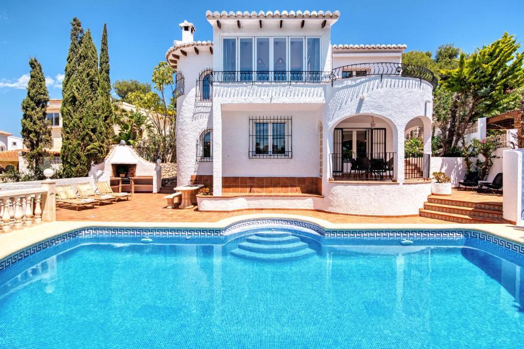 a villa with a swimming pool in front of a house at Casa Crystal in Jávea