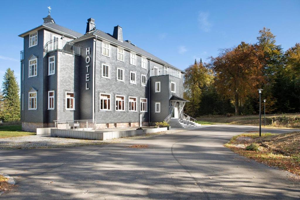 a large gray building on the side of a road at Kurhaus Masserberg in Masserberg