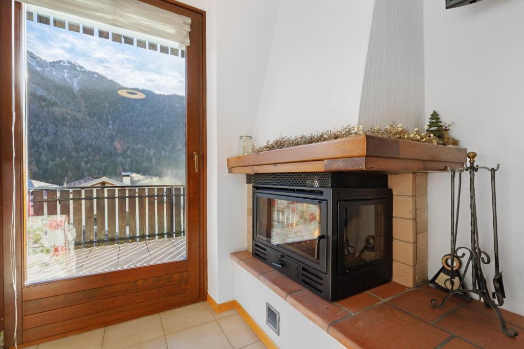 a living room with a fireplace and a window at La finestra sui monti - Breguzzo in Breguzzo