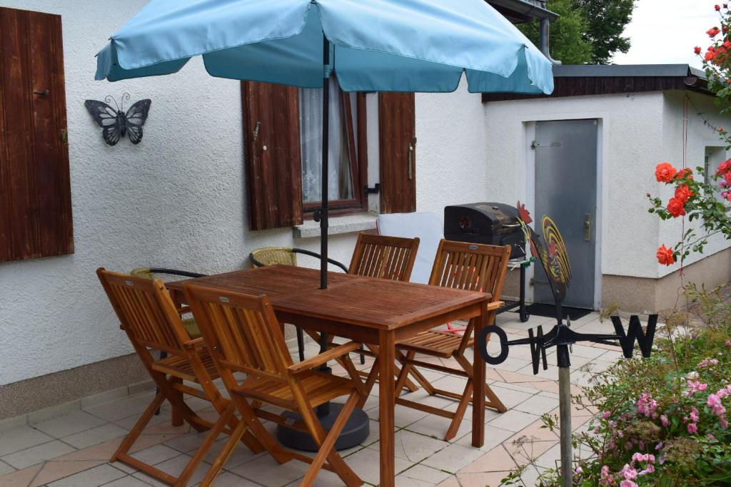 a wooden table and chairs with a blue umbrella at Landhaus Eva-maria in Elbingerode